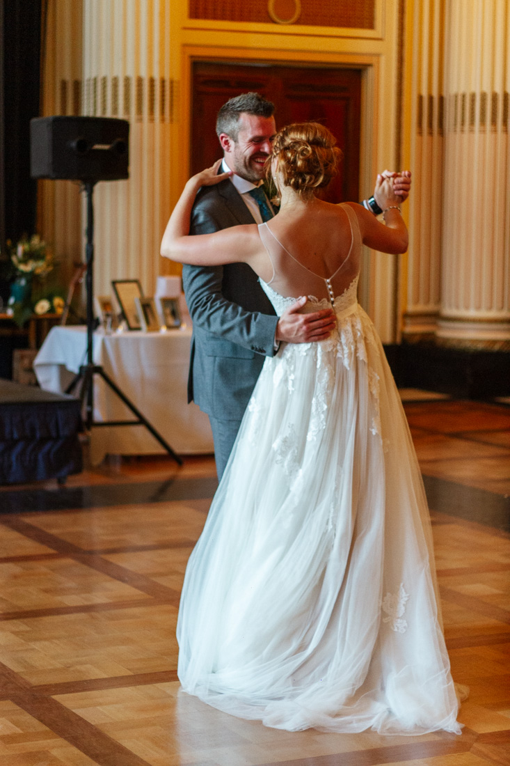 bride and groom are dancing together and smiling on a grand dancefloor