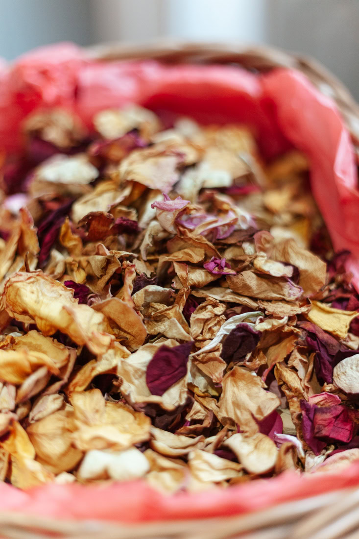 Basket filled with dried rose petals, lined with red cloth, DIY wedding confetti.