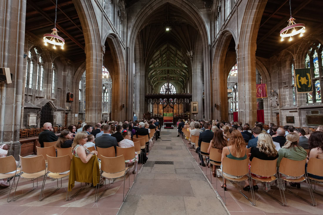 Guests seated in rows inside st mary's church with high arches and stained glass windows during a wedding ceremony.
