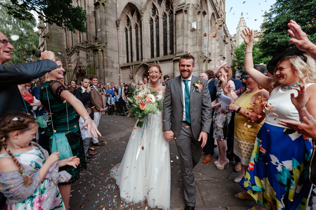 Wedding couple walks past cheering guests outside St Marys church as confetti fills the air in celebration.