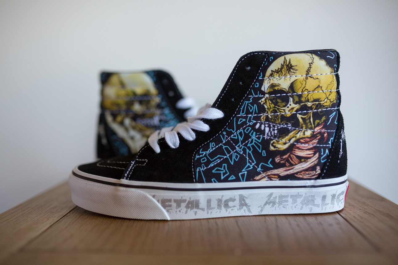 Black high‑top custom converse with bold metallica skull and geometric artwork displayed on a wooden surface