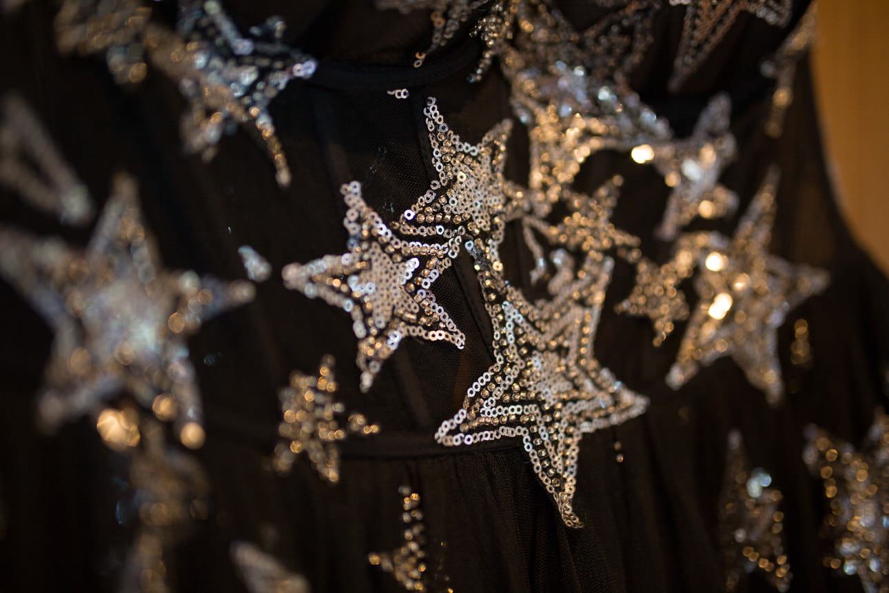 Close‑up of black wedding dress fabric covered in shimmering silver sequin stars of varying sizes
