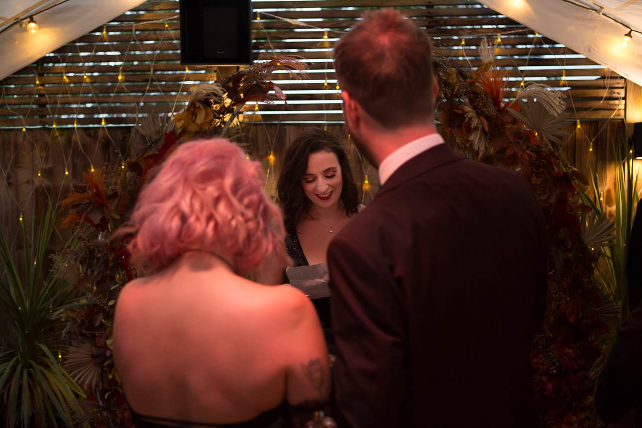 friend does a reading for couple during wedding ceremony at Beartown Tap pub beer garden