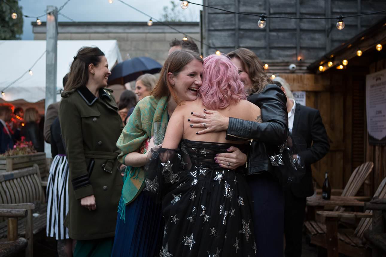 three girls share a hug after a wedding ceremony at Beartown Tap pub beer garden