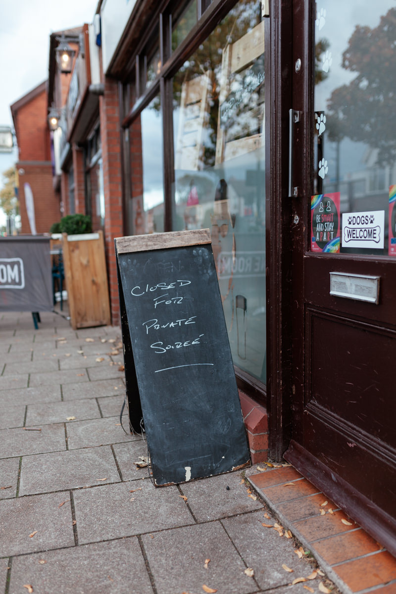 A chalkboard outside a shop reads “Closed for private soirée” beside a door with stickers.