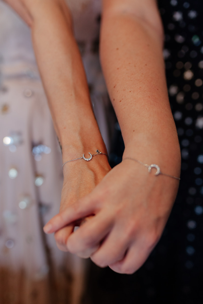 two women hold hands wearing matching lucky hourseshoe bracelets