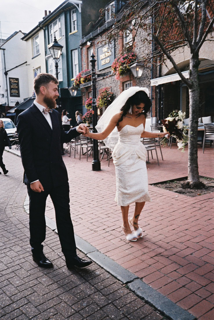 Couple walk hand-in-hand past pub a happy moment in Brighton street; shot on 35mm film.