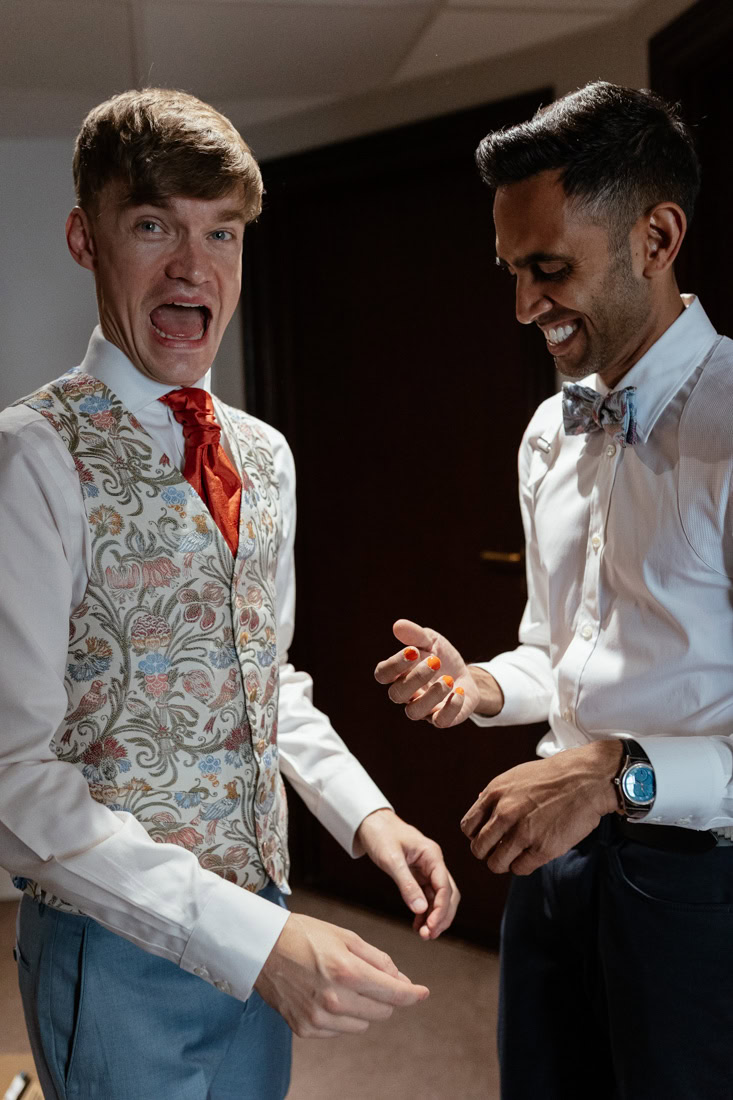Two formally dressed people share a light hearted moment in a hallway.